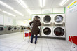 woman put laundry in washing machine in public laundry