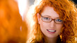 Attractive girl wearing glasses looking at a mirror.