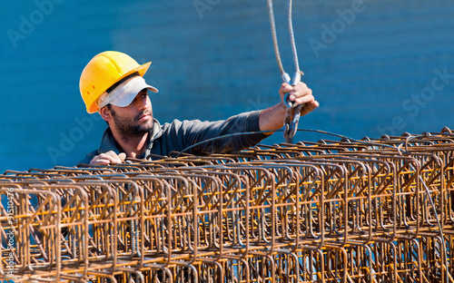 Photo: Construction worker loading stack of reinforcement beam cages to Construction worker loading stack of reinforcement beam cages to