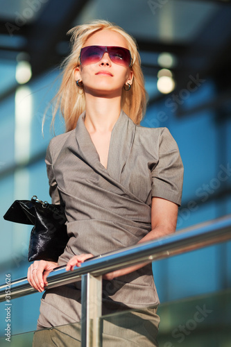 Photo: Young businesswoman against office windows Young businesswoman against office windows