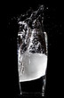 Ice splashing into a glass of water on a black background