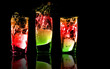 Three exotic tropical cocktails with reflections on black