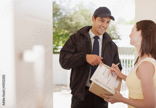 Photo: Woman signing box receipt for delivery man Woman signing box receipt for delivery man