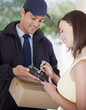 Photo: Woman signing for box from delivery man Woman signing for box from delivery man