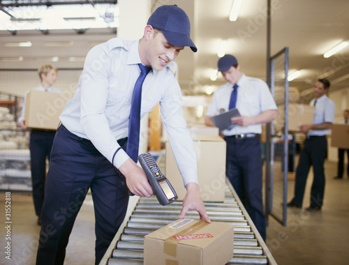 Photo: Worker scanning box on conveyor belt in shipping area Worker scanning box on conveyor belt in shipping area