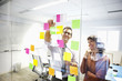 Business people looking at adhesive notes in conference room