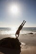 Man doing handstand on rock at beach