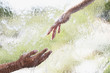Two hands reaching out behind glass