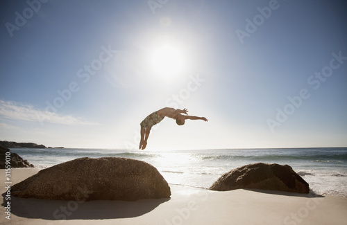 Photo: Man doing backflip on beach Man doing backflip on beach