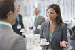 Businesswoman drinking coffee and talking to co-worker