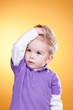 Disturbed little boy holding head with hand