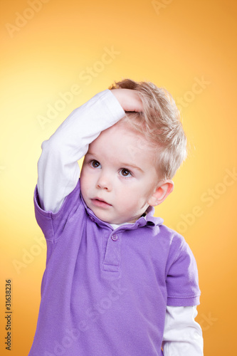 Photo: Disturbed little boy holding head with hand Disturbed little boy holding head with hand