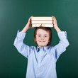 kleines schulkind balanciert bücher auf dem kopf
