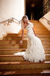 Beautiful girl in a wedding dress going down the stairs