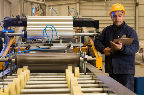 Foto: Factory worker processing roll of steel sheet. Factory worker processing roll of steel sheet.