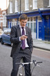 Foto: A businessman on his bicycle, looking his phone A businessman on his bicycle, looking his phone