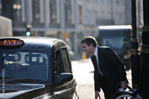 Photo: A businessman with his folded bicycle, talking to a taxi driver A businessman with his folded bicycle, talking to a taxi driver
