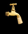 Old gold faucet closed with cork isolated on black