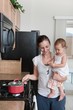 A Mother Cooking And Holding A Baby