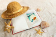 Book with straw hat and seashells in sand Book with straw hat and seashells in sand