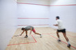 Squash players in action on a squash court Squash players in action on a squash court
