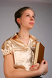 Girl holding book looks forward.