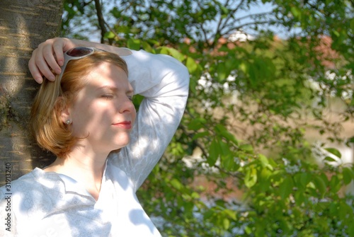 Foto: Young woman relaxing at a tree Young woman relaxing at a tree