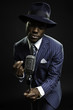 Black man with blue striped suit and blue hat singing.