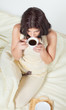 Young woman sitting in bed drinking coffee