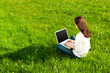 Frau sitzt mit Laptop auf einer Wiese