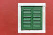 Single window with green shutters set in red wall in Skradin
