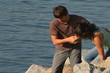 Young couple climbing rocks by water
