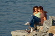 Young couple climbing rocks by water