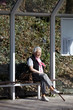 Nette alte Dame in Bushaltestelle