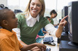 Teacher helping kindergarten children learn how to use computers