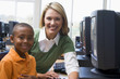 Teacher helping kindergarten children learn how to use computers