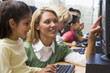 Teacher helping kindergarten children learn how to use computers