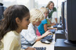 Children at computer terminals with teacher in background