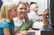 Teacher helping kindergarten children learn how to use computers