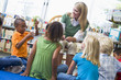 Kindergarten teacher and children looking at seedling in library