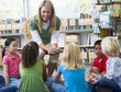 Kindergarten teacher and children looking at bird's nest in libr