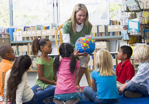 Photo: Kindergarten teacher and children looking at globe in library Kindergarten teacher and children looking at globe in library