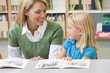 Kindergarten teacher helping student with reading skills
