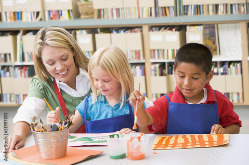 Photo: Kindergarten teacher sitting with students in art class Kindergarten teacher sitting with students in art class