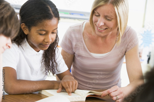 Photo: A schoolgirl and her teacher reading a book in class A schoolgirl and her teacher reading a book in class
