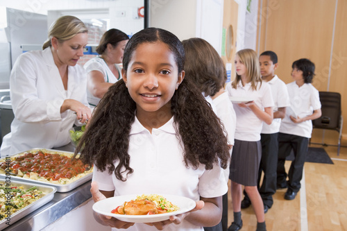 Photo: Schoolgirl holding plate of lunch in school cafeteria Schoolgirl holding plate of lunch in school cafeteria