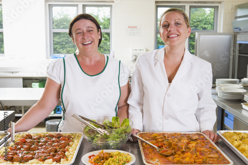 Photo: Lunchladies beside trays of food in school cafeteria Lunchladies beside trays of food in school cafeteria
