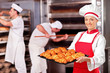 Female baker holding freshly baked croissants in bakery Female baker holding freshly baked croissants in bakery