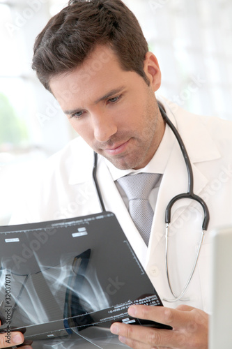 Photo: Portrait of young doctor checking X-Ray Portrait of young doctor checking X-Ray