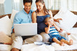 Couple using laptop with son eating watermelon